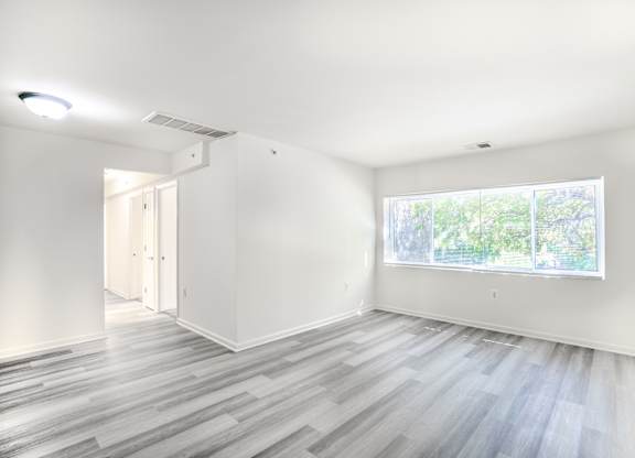 A room with a window and a wooden floor.