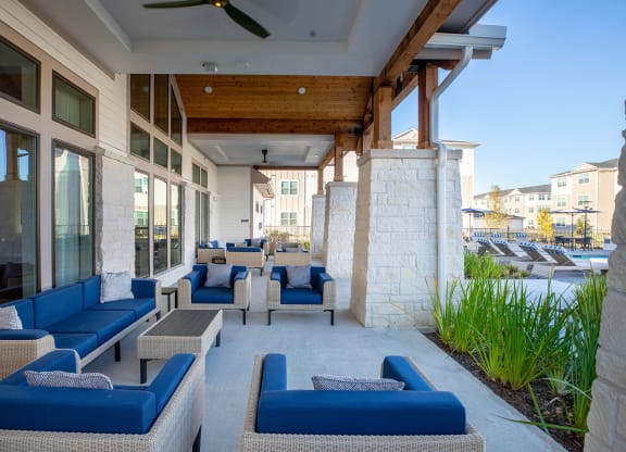 a patio with blue couches and chairs and a pool in the background at 55 Fifty at Northwest Crossing, Texas, 77092