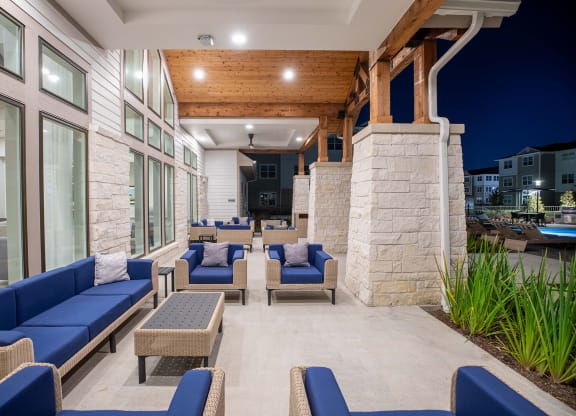 a patio with blue couches and chairs and a pool in the background at 55 Fifty at Northwest Crossing, Houston, 77092