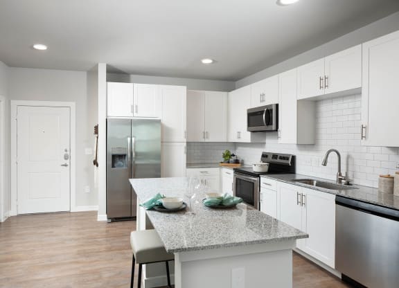 a kitchen with white cabinets and a granite counter top at 55 Fifty at Northwest Crossing, Houston