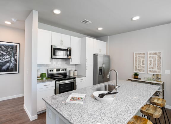 a kitchen with white cabinets and a granite counter top at 55 Fifty at Northwest Crossing, Houston, TX