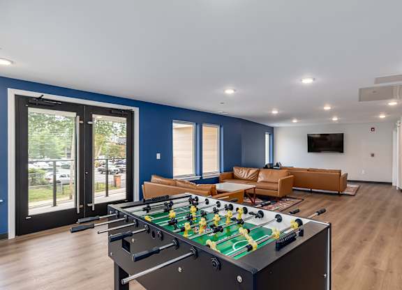 A foosball table is in the middle of a room with a couch and a pool table.