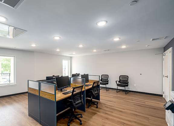 A room with a desk, chairs, and computers.