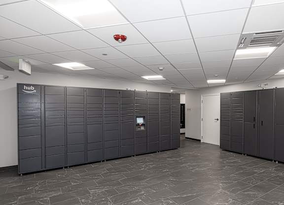A room with a white ceiling and grey flooring with a row of cupboards on the wall.