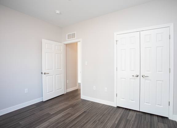 A room with a white door and a brown floor at MLK Apartments, Hartford, 06106