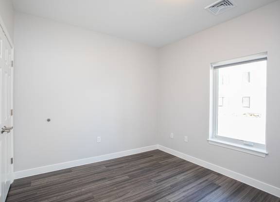 A room with a white door, a window, and a wooden floor at MLK Apartments, Hartford, 06106