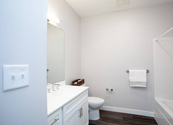 A white bathroom with a toilet, sink, and mirror at MLK Apartments, Hartford, 06106