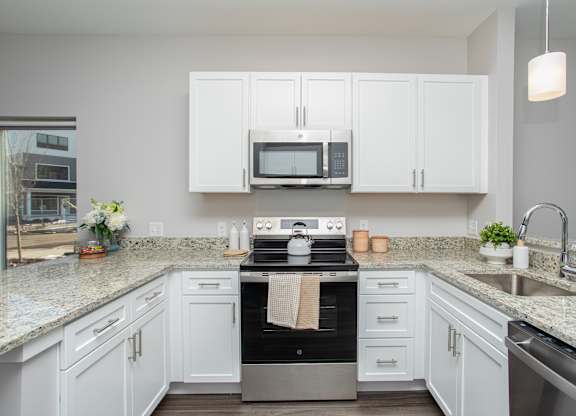 A kitchen with white cabinets and a granite countertop at MLK Apartments, Hartford, 06106