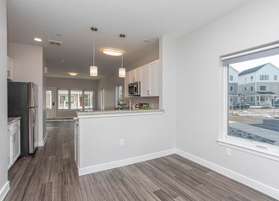 A spacious kitchen and living room with wood flooring and white walls at MLK Apartments, Hartford, 06106