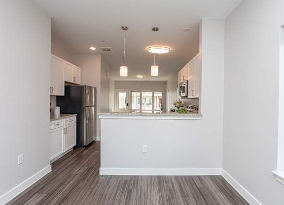 A kitchen with white cabinets and a wooden floor at MLK Apartments, Hartford, 06106
