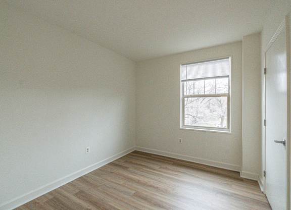 A room with a window and wooden flooring.