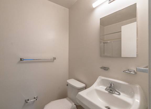 A white toilet sits next to a white sink in a small bathroom.
