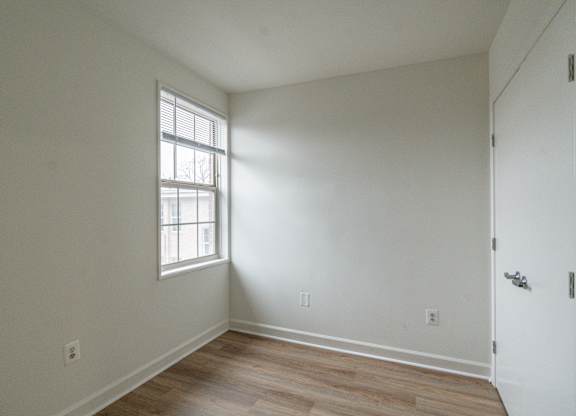 A room with a window and wooden flooring.