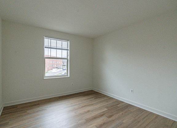 Empty room with a window and wooden flooring.
