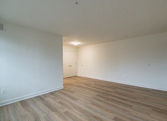 A room with wooden flooring and a door on the left side.