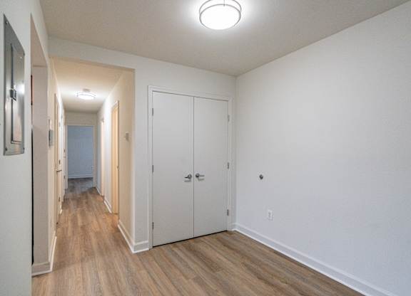 A hallway with white walls and wood floors.