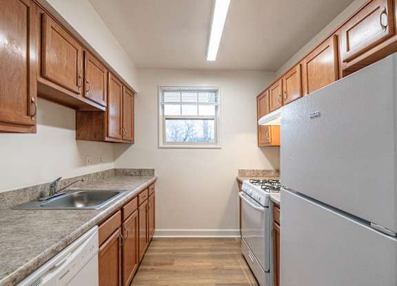 A kitchen with a white fridge and wooden cabinets.