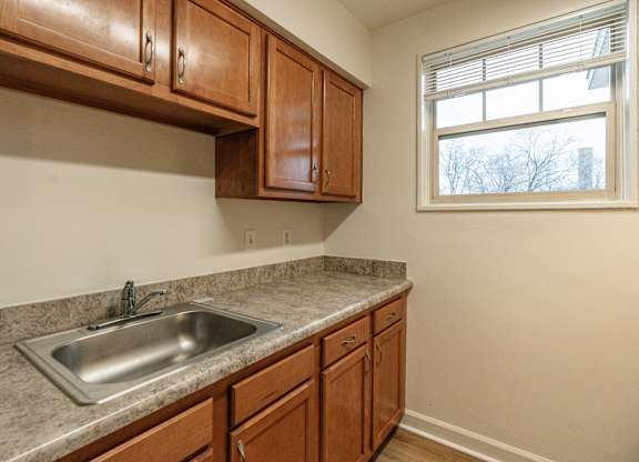 A kitchen with brown cabinets and a silver sink.