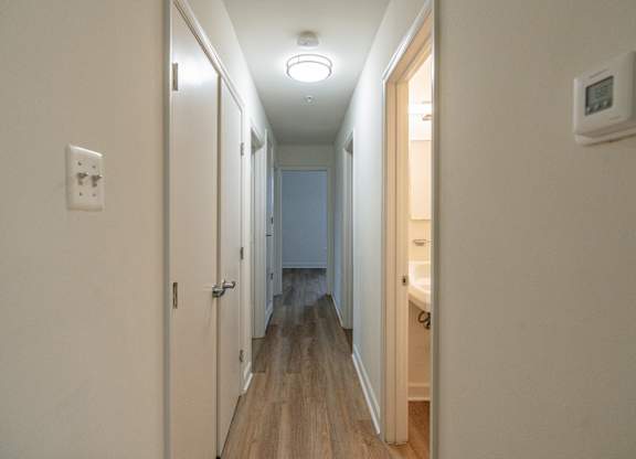A long hallway with a light on the ceiling and a door on the right.