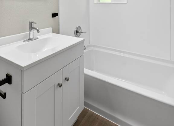 Newly remodeled modern style bathroom with a sink, mirror, and bathtub at Horizon Park Apartments