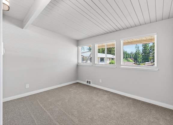 Bedroom a carpeted floor and a window showing a view of trees and a house at Horizon Park Apartments