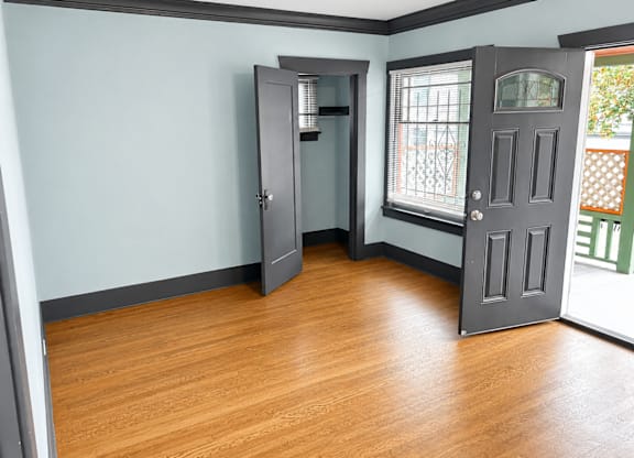 4729Roosevelt LivingRm view from Fireplace with a grey door and wood plank flooring.