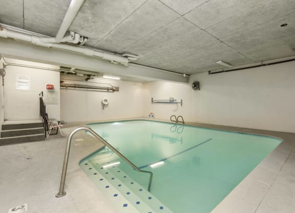 an indoor swimming pool in a building with white walls and concrete floors