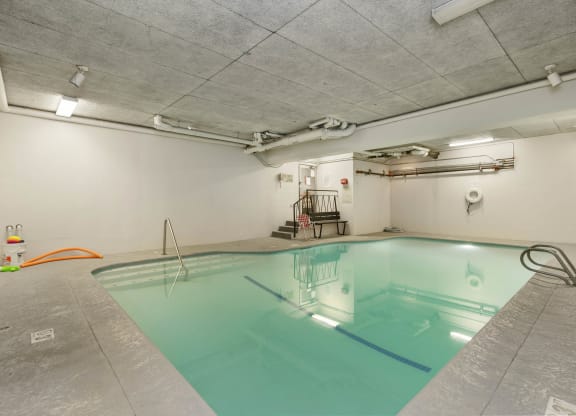 a swimming pool in a room with white walls and concrete floors