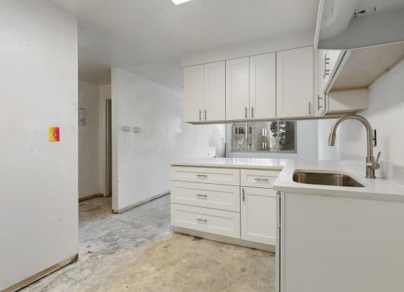 an empty kitchen with white cabinets and a sink