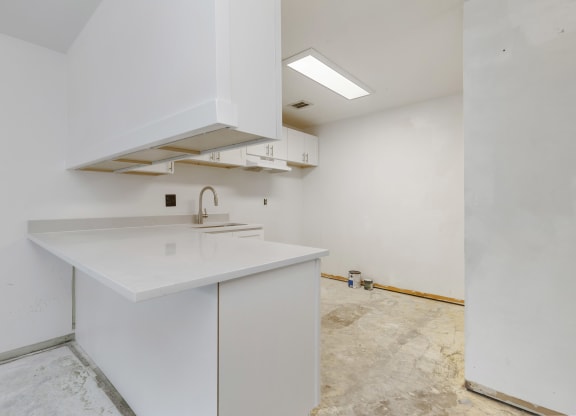 the kitchen is being remodeled with white cabinets and white counter tops and a sink