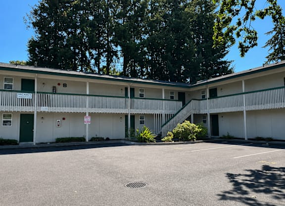 A parking lot in front of a white building with green doors.