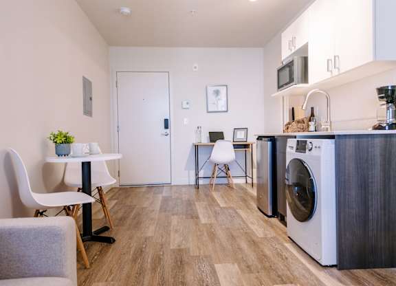 ADA accessible studio apartment at Bode125 with minimalist kitchen with stainless steel appliances, small eat-in kitchen table and desk on back wall