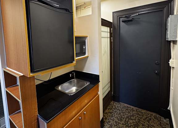 A small kitchen with a sink and a television.
