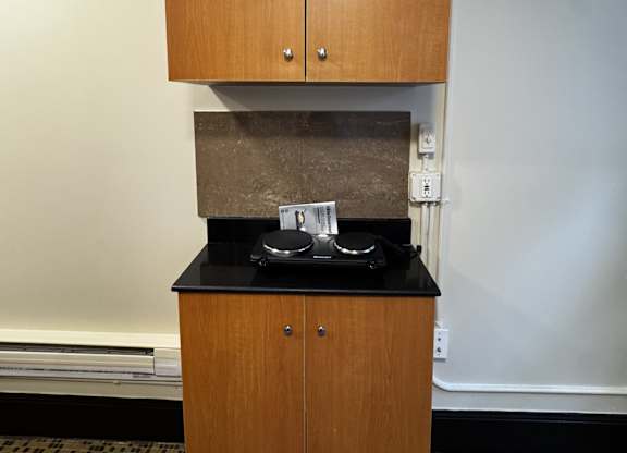 A brown cabinet with a black counter on top of it.
