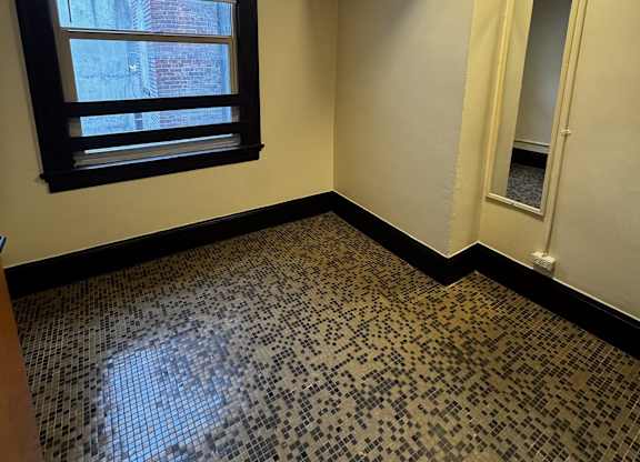 A room with a black and white tiled floor and a window.