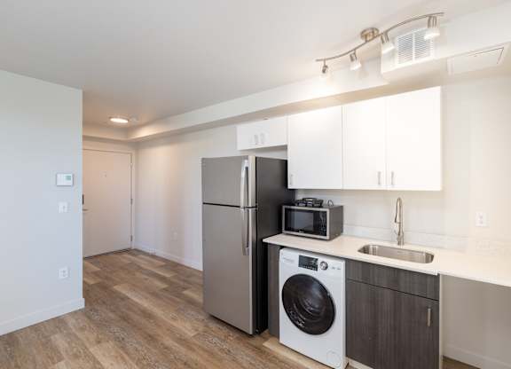 A kitchen with a refrigerator, microwave, and washing machine.