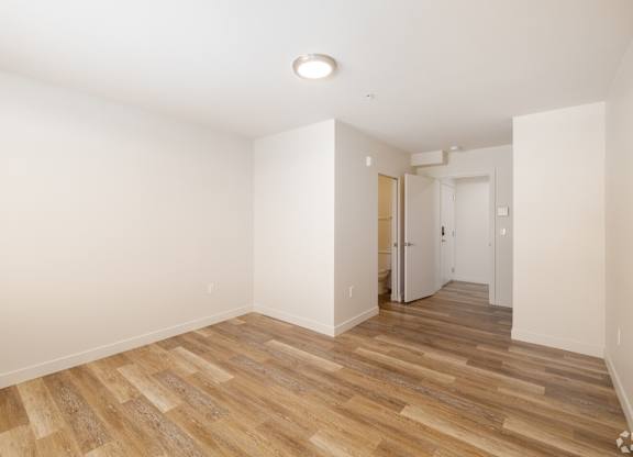 A room with wooden flooring and white walls.