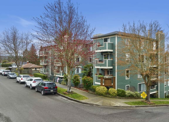 a green apartment building with cars parked in front of it