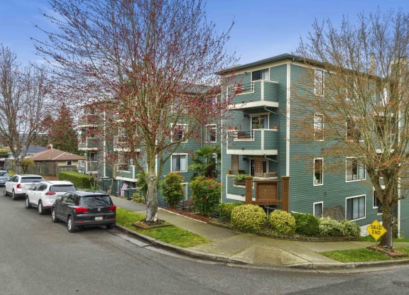 a green apartment building with cars parked in front of it