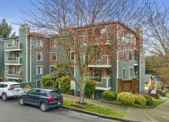 a large green apartment building with cars parked in front