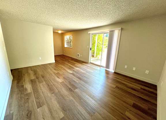 2-bedroom living room space at Bridgeport Terrace Apartments with wood plank vinyl floors and sliding glass window to patio.