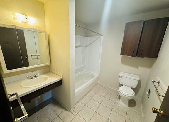 Bathroom in 1-bedroom apartment at Bridgeport Terrace with single-sink vanity, large mirror, tub/shower combo, tile flooring, and wall-mounted storage cabinet.