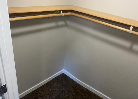 Large closet with white walls and bar to hang clothes in 1-bedroom apartment.