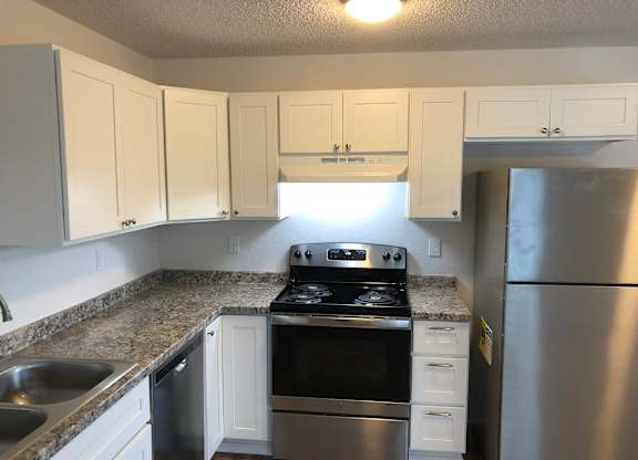 Studio kitchen with white cabinets and stainless steel appliances.