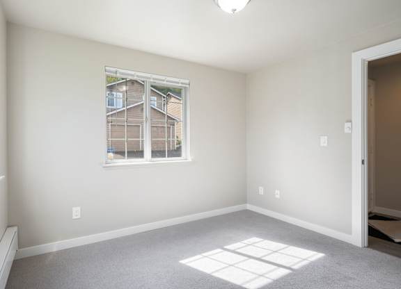 A room with a window and a carpeted floor.