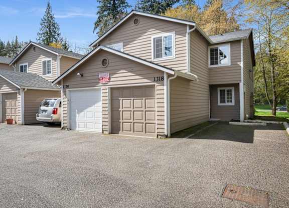 A house with a garage and a car parked in front.