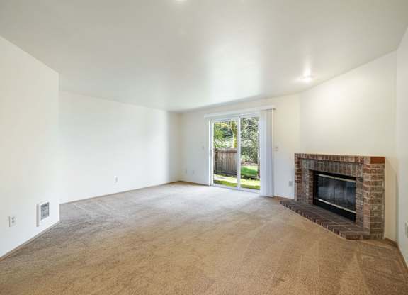 A large empty room with a fireplace and sliding glass doors.