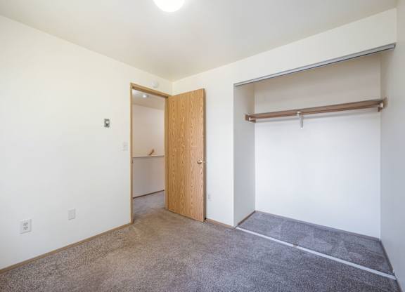 A room with a carpeted floor and a wooden door.