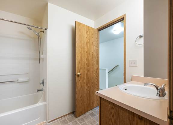 A bathroom with a white tub and a wooden door.