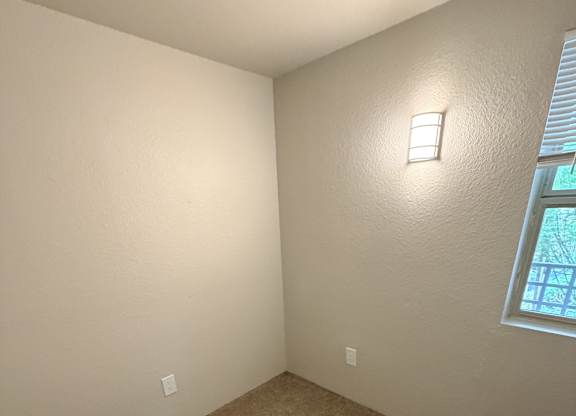 A room with a carpeted floor and a window with blinds.